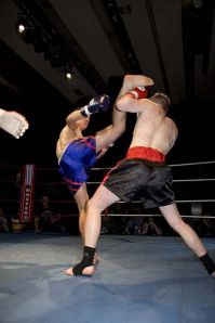 High kick and block. Kieran Shangnessy (Master A's, blue trunks) vs. Andy Snell (Kings gym, black trunks). Photograph originally published on masteramuaythai.co.uk